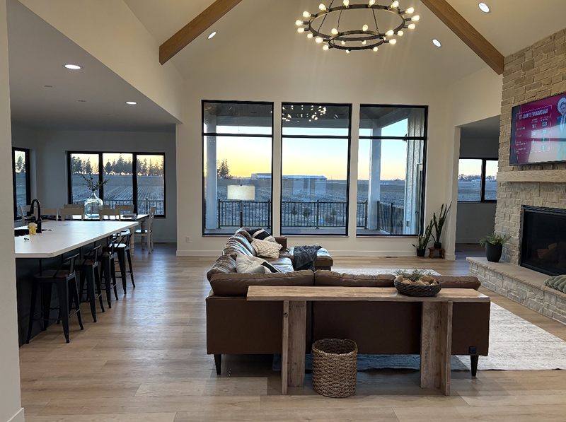 Vaulted great room with exposed beams, a chandelier and a stone fireplace